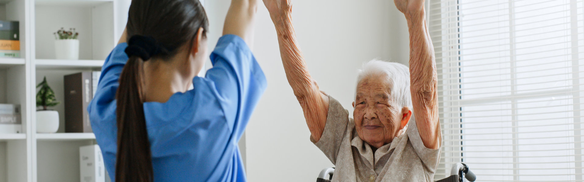 Caregiver helping the elderly woman do some exercises