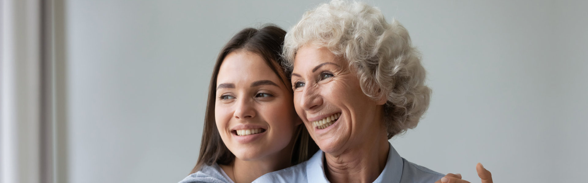 Beautiful woman hugging an elderly woman looking at the window