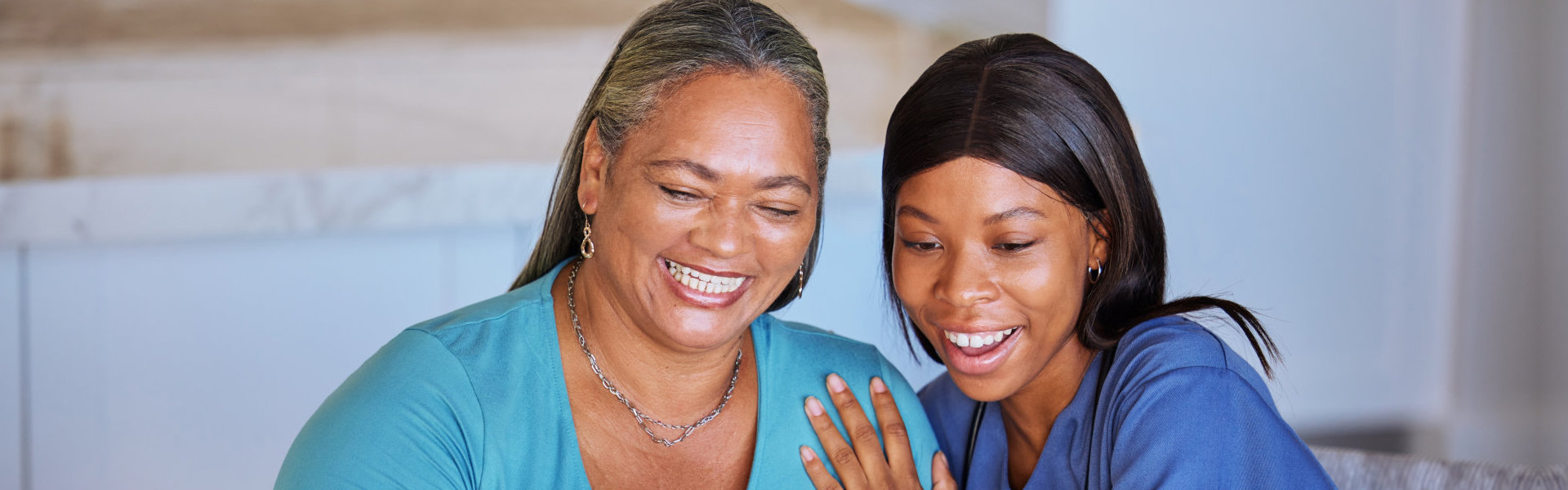 Happy senior woman and caregiver with laptop